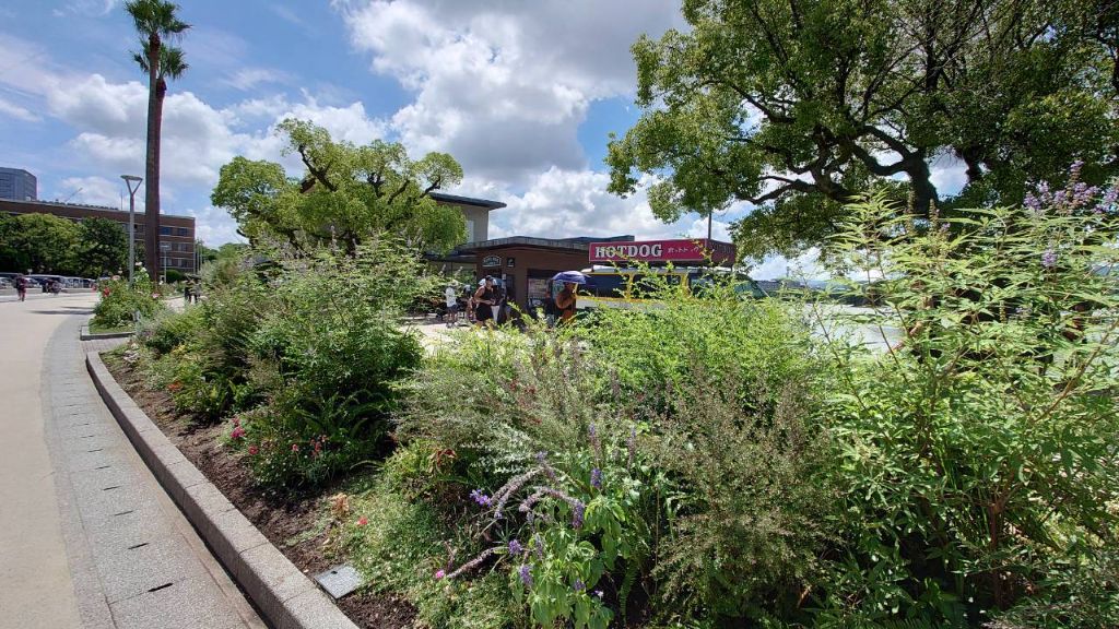 緑豊かな花壇と屋台のある公園風景